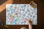 Child coloring a beach-themed coloring book with crayons on a wooden table.
