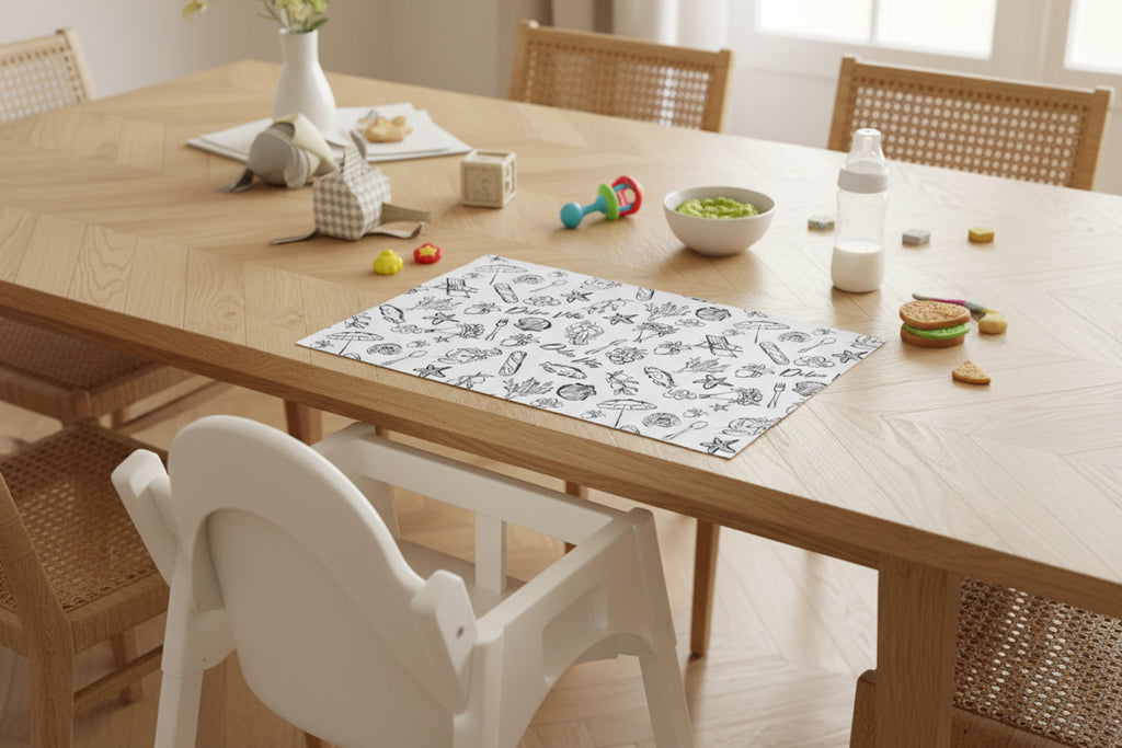 Wooden dining table with a placemat, toys, and a bottle on a light wood floor.