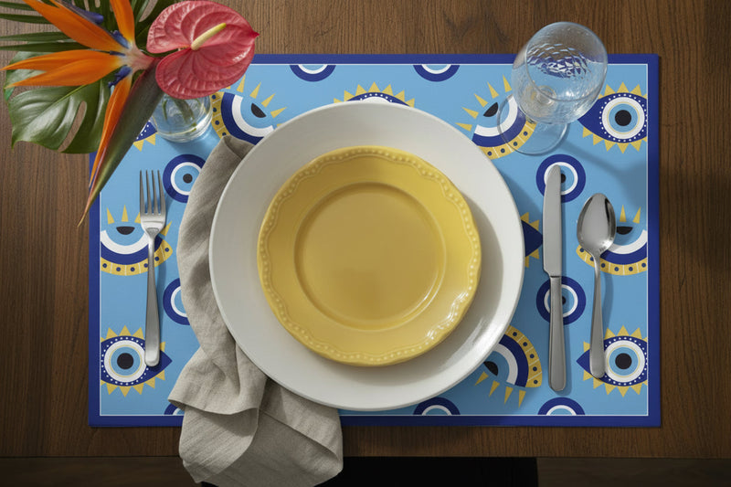 Table setting with yellow plate, white bowl, silverware, and colorful placemat on a wooden table.