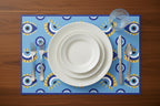 Dinner setting with white plates, silverware, and a blue placemat with geometric patterns on a wooden table.