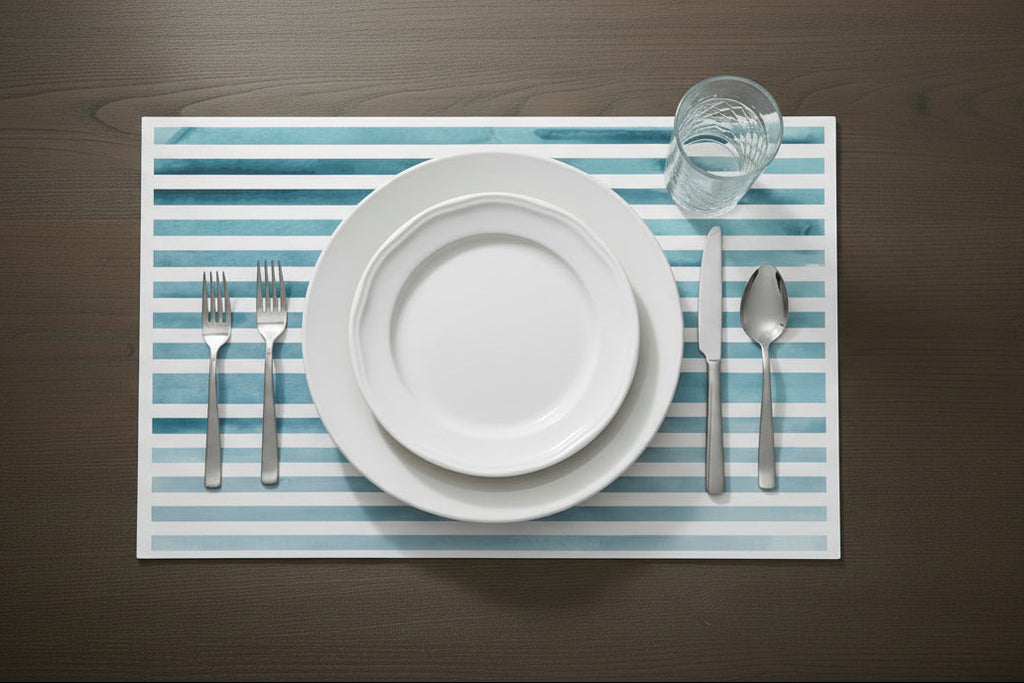 Dining setup with white plates, silverware, and a glass on a striped placemat.