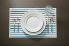 Dining setup with white plates, silverware, and a glass on a striped placemat.