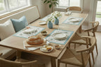 Dining table set with plates, bread, and glasses in a bright room.