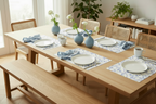 Dining table set with plates, cups, and floral blue bow placemats in a bright room.