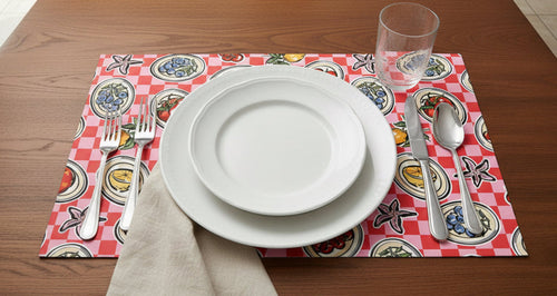 Dinner setting with white plates, silverware, and a red checkered placemat on a wooden table.