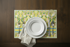 Table setting with a decorative placemat featuring floral patterns on a wooden table.