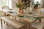 Paper placemat with tropical leaf pattern on a green border set on a wooden table with terracotta plates
