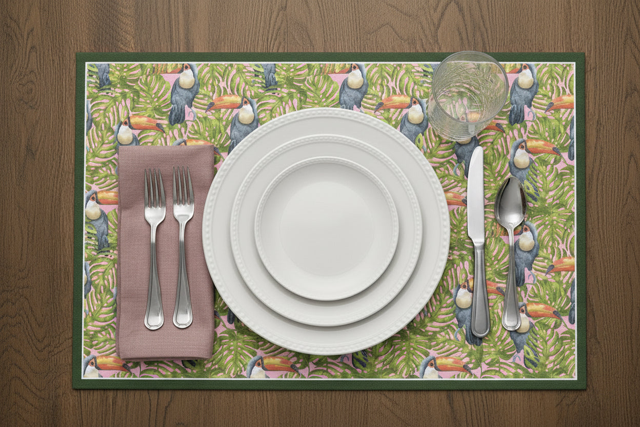 Placemat with bird pattern featuring a set of white plates, silverware, and a pink napkin on a wooden surface.